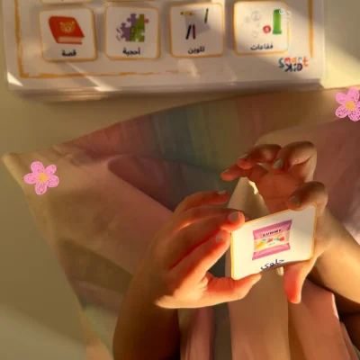 A girl holding a sweets card from the Arabic hobbies and favourite things cards