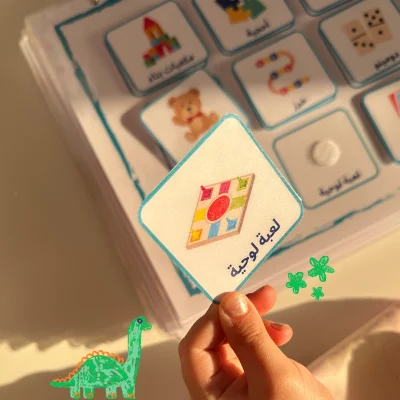 A girl holding a board game card from the Arabic games and activities cards