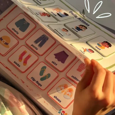 A girl turning interactive pages showing clothes and daily actions in English